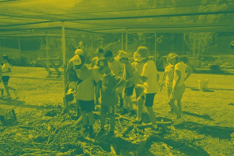 Grupo de niños y niñas buscando fósiles bajo una carpa